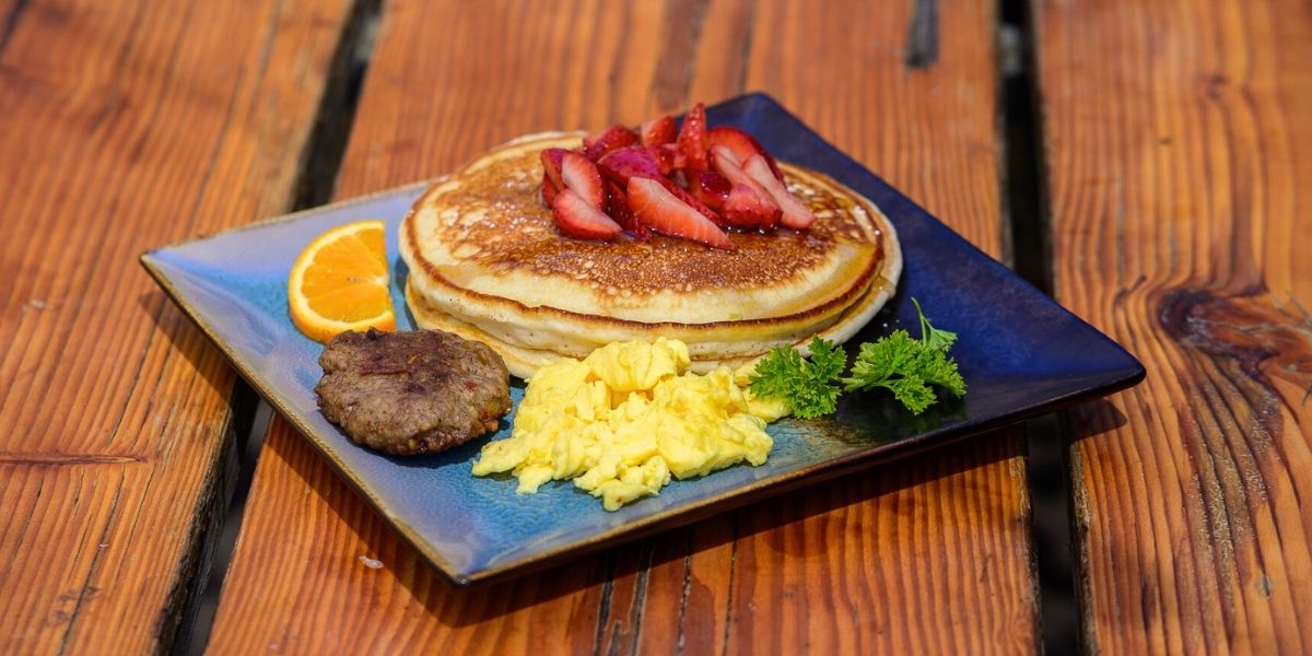 A hearty lumberjack stack of pancakes with eggs and sausage your way makes the day.
